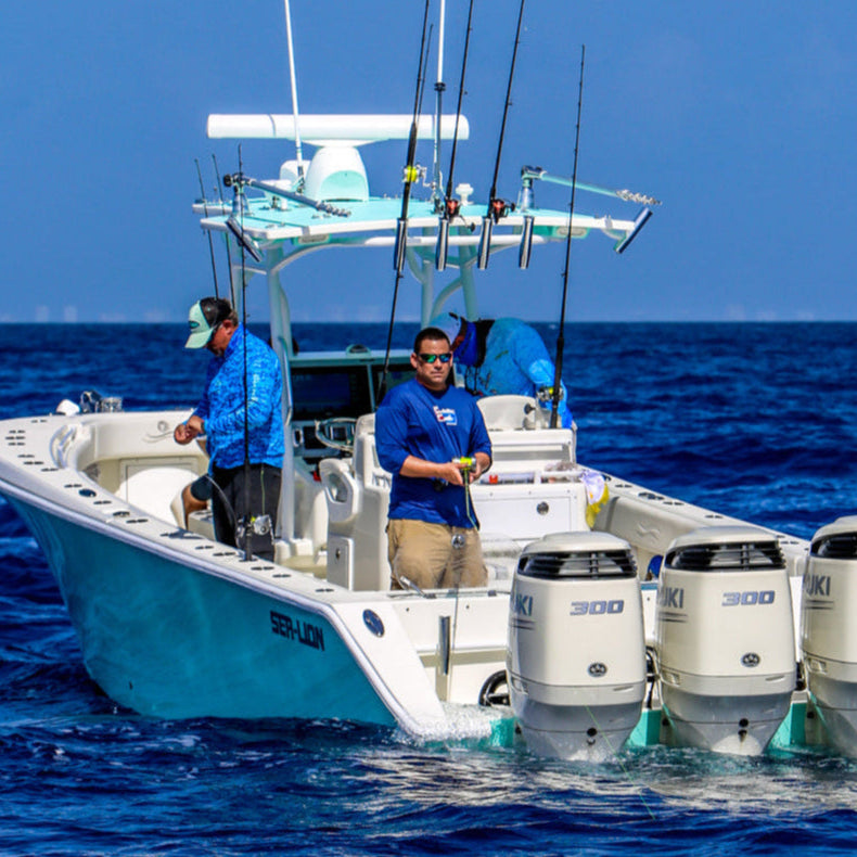 Two men on a boat with three outboard motors in the open ocean.