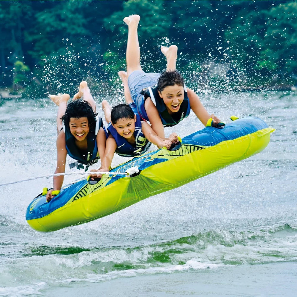 Three people on a yellow and blue inflatable water board in the water.