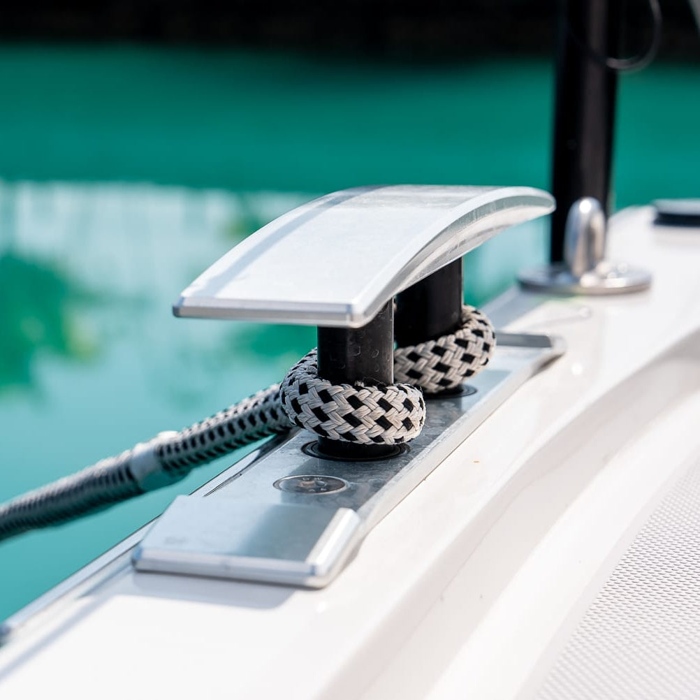 Close-up of a boat cleat with a rope on a dock with water in the background