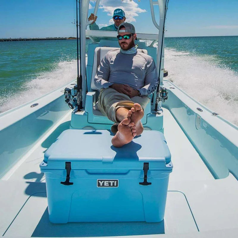 Person sitting on a boat with a YETI cooler in the foreground, ocean in the background