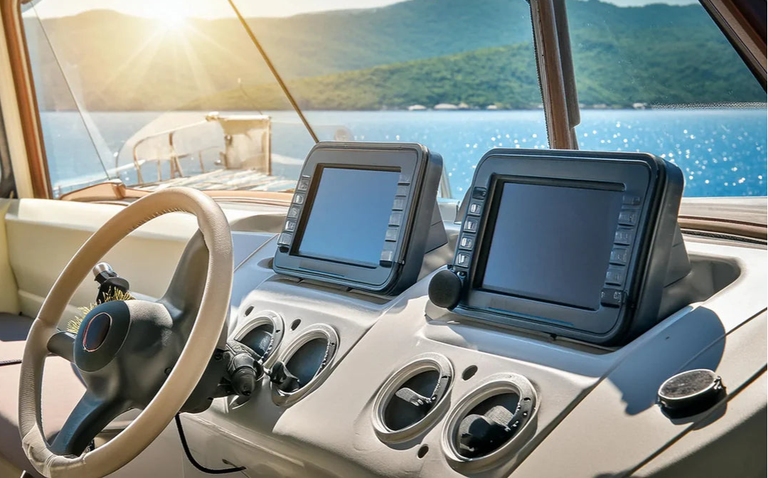 Boat interior with steering wheel and dashboard view of a scenic water body.