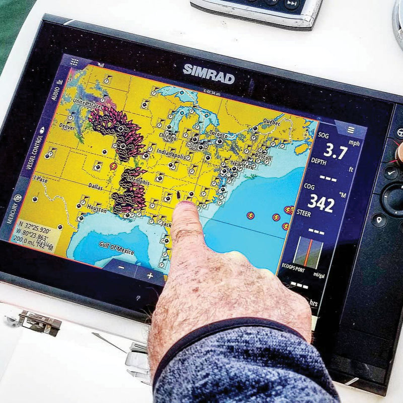 Person using a Simrad marine navigation display with a map on a boat.