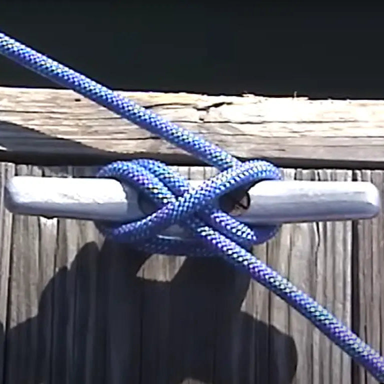 Blue rope tied around a metal cleat on a wooden surface