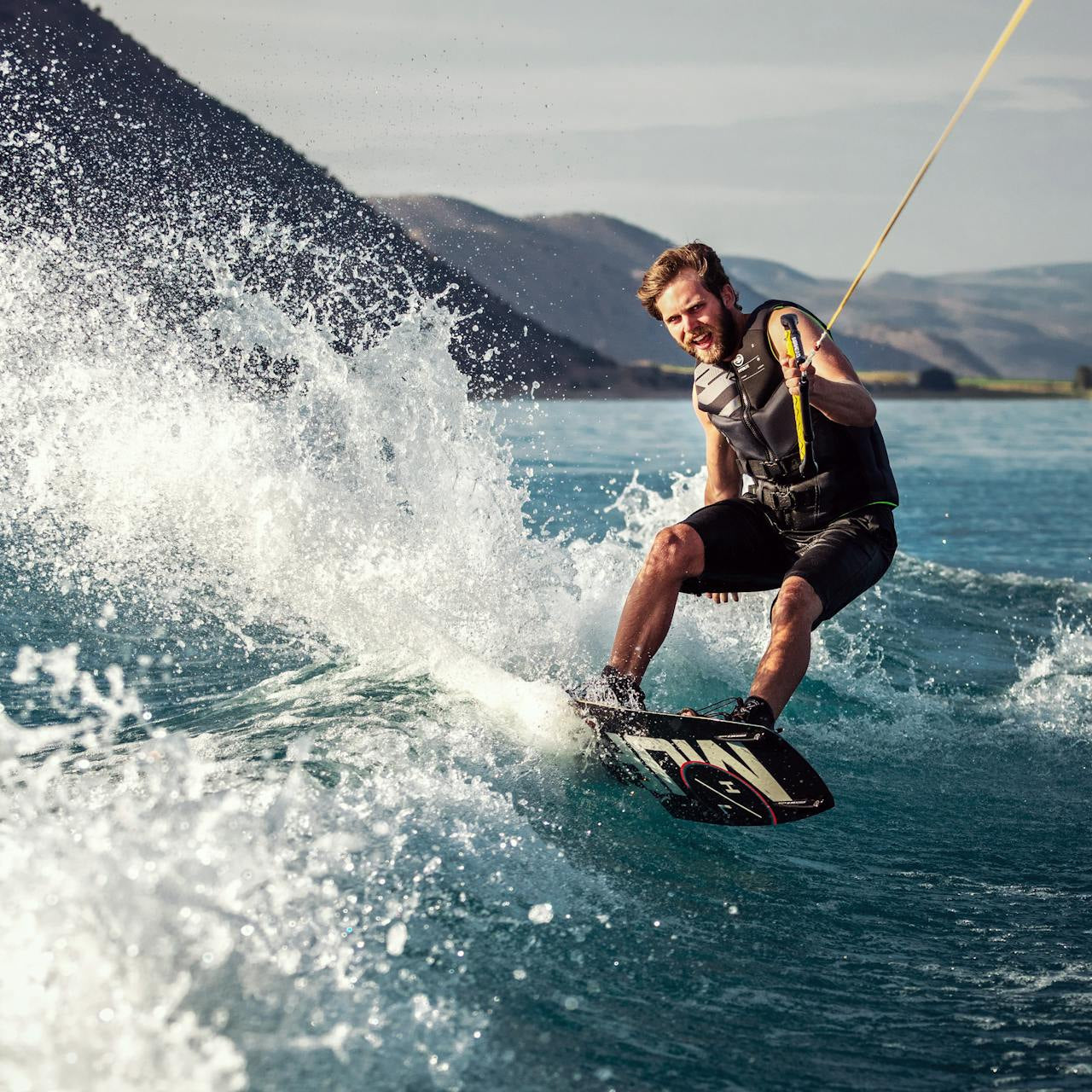 Person wakeboarding on a body of water with mountains in the background